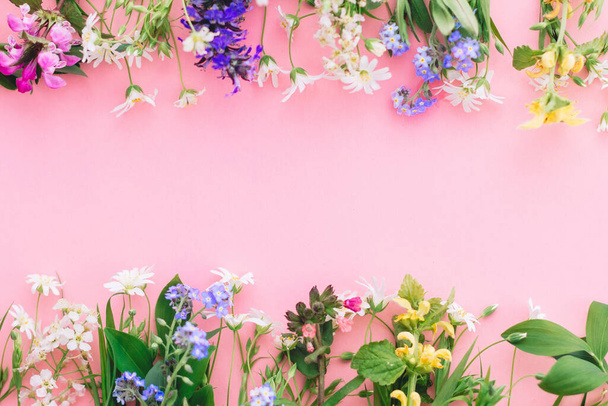 Floral flat lay frame de flores silvestres primavera no fundo de papel rosa, espaço para texto. Modelo de cartão de saudação floral. O conceito do dia da mãe feliz. Olá primavera. Flores coloridas florescendo
 - Foto, Imagem