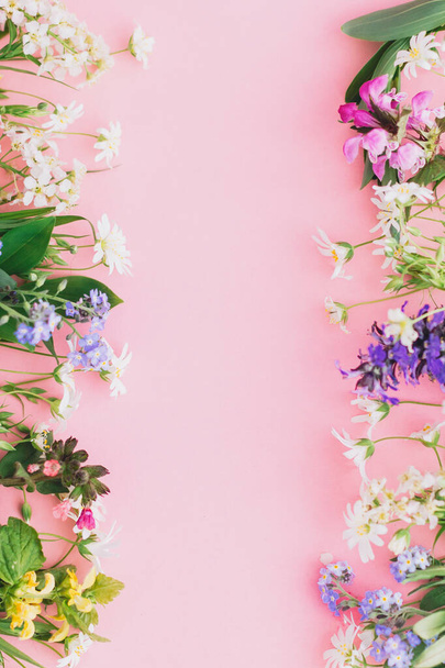 Floral flat lay frame de flores silvestres primavera no fundo de papel rosa, espaço para texto. Modelo de cartão de saudação floral. O conceito do dia da mãe feliz. Olá primavera. Flores coloridas florescendo
 - Foto, Imagem