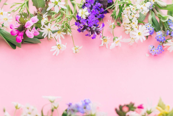 Wildflowers πολύχρωμο πλαίσιο σε ροζ χάρτινο φόντο με χώρο για κείμενο. Ανθισμένα ανοιξιάτικα λουλούδια, floral ευχετήριες κάρτες. Καλή ιδέα για την Ημέρα της Μητέρας. Γεια σου άνοιξη - Φωτογραφία, εικόνα