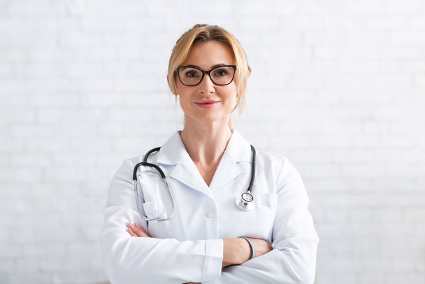 Il paziente consulta il medico tramite videochiamata. Medico donna in cappotto bianco con braccia incrociate - Foto, immagini