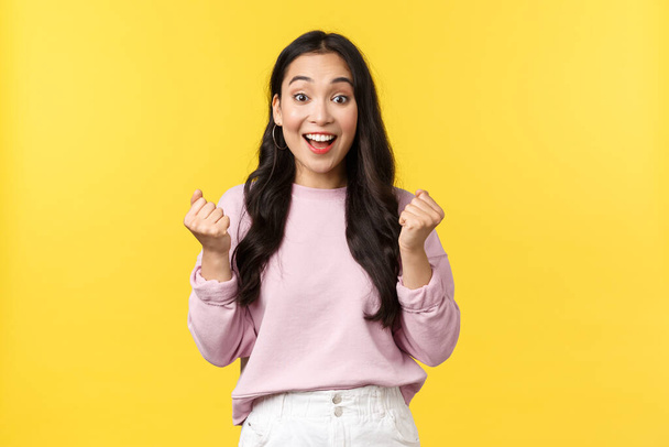 Lifestyle, emotions and advertisement concept. Cheerful and excited cute asian girl winning lottery, feel luck and upbeat, triumphing over achievement, say yes and fist pump rejoicing - Photo, Image