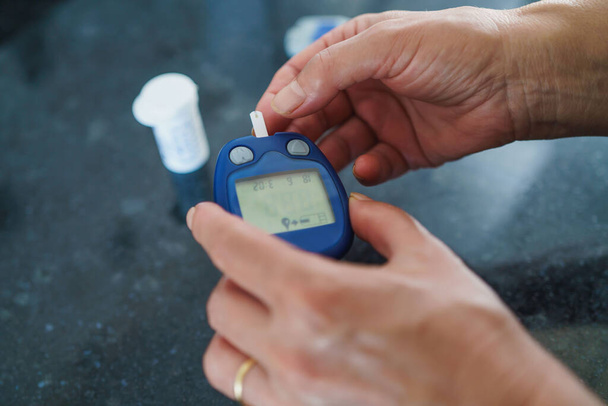 Lääkkeet, diabetes, glykemia, terveydenhuolto ja ihmisten käsite lähikuva naisesta, joka käyttää lancelet-sormea verensokerin mittaamiseen glukoosimittarilla - Valokuva, kuva