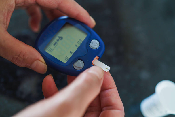 Gyógyszer, Cukorbetegség, Glikémia, Egészségügyi és az emberek koncepció - közelkép a nő segítségével lancelet az ujját, hogy ellenőrizze a vércukorszintet glükózmérő - Fotó, kép