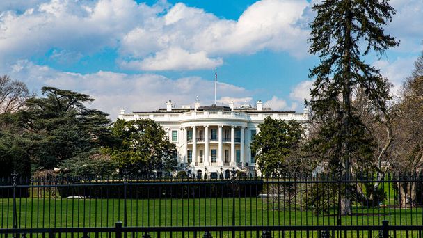 Vista da Casa Branca, residência presidencial e Sala Oval do gramado sul em Washington DC com cerca de segurança de ferro em primeiro plano
 - Foto, Imagem