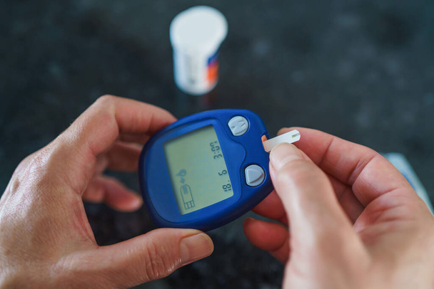 医学、糖尿病、血糖値、医療や人々の概念-血糖値計によって血糖値をチェックするために指の上にランセットを使用して女性のクローズアップ - 写真・画像