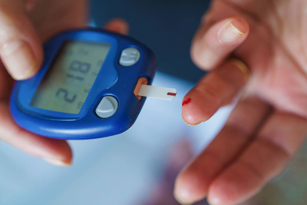 Medicine, Diabetes, Glycemia, Health care and people concept - close up of female using lancelet on finger to checking blood sugar level by Glucose meter - Foto, immagini