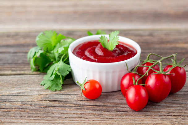 Bol blanc de sauce tomate avec persil et tomate. Ketchup sur fond de bois naturel. Espace de copie - Photo, image