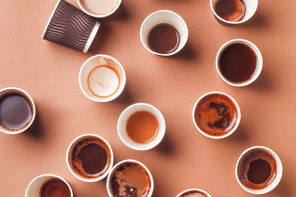 Tazas de café vacías y llenas con diferentes tipos de café, capuchino y macchiato sobre fondo beige. Vista superior, plano
. - Foto, imagen