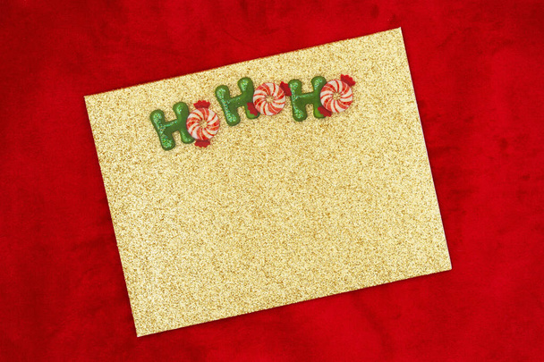 Goldglitzer-Grußkarte mit Minzen auf rotem Plüschstoff-Attrappe mit Kopierplatz für Weihnachts- oder Urlaubsbotschaft  - Foto, Bild