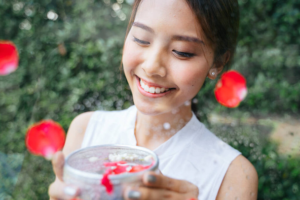 Atkuyruklu kadın gülümsüyor Çiçekli su üzerine sıçrarken. - Fotoğraf, Görsel