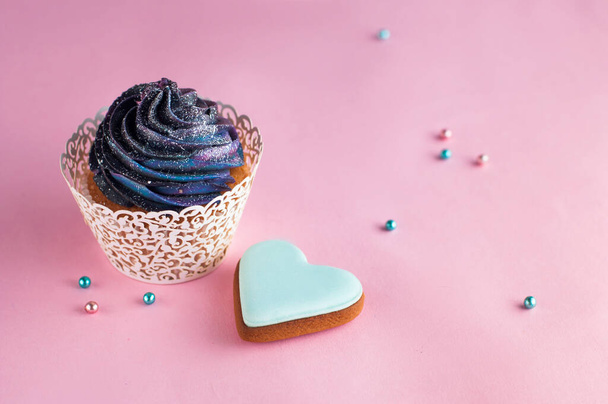 Cupcake with galaxy whipped cream near heart shape cookie on party background with copyspace - Foto, Imagem