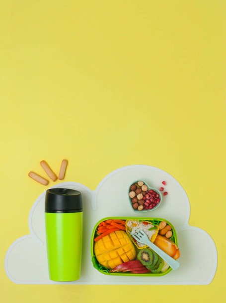 Sağlıklı gıda kavramı: Pirinç, taze meyve ve sebzeli açık beslenme çantası ve sarı zemin üzerinde yazı için boş alanı olan termo bardak; üst görünüm, düz yatış - Fotoğraf, Görsel
