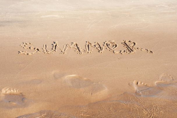 The inscription summer on the sand by the water. Photos on the beach on a Sunny day - 写真・画像