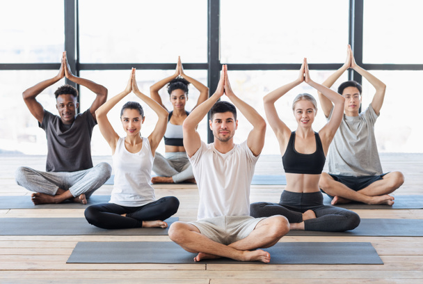 Junge Leute praktizieren Yoga in der Gruppe, sitzen in Baumpose im Studio - Foto, Bild