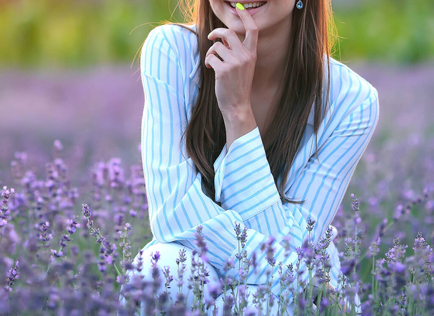 Nuori tyylikäs ja viehättävä valkoihoinen tyttö valkoisessa raidallisessa paidassa lepää laventelipellolla auringonlaskun aikaan. Muoti ja tyyli käsite. - Valokuva, kuva
