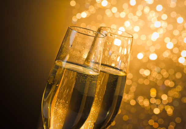 detail of champagne flutes with golden bubbles on dark golden light bokeh background - Fotoğraf, Görsel
