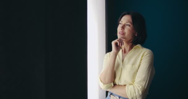 Woman looking very thoughtful while standing near window - Video, Çekim