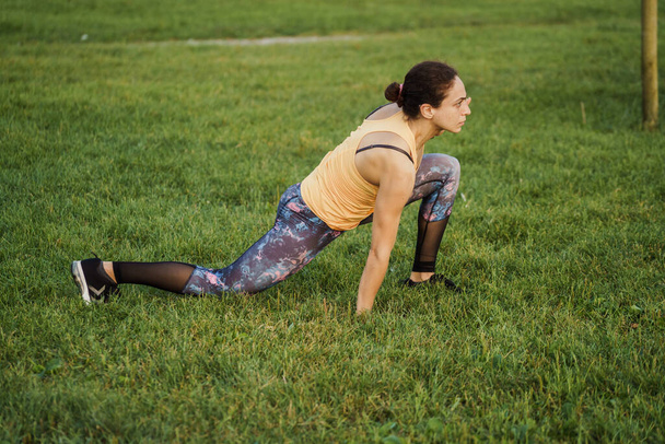 Running young woman seaside sunset, doing aerobics and yoga at park - Foto, Imagem