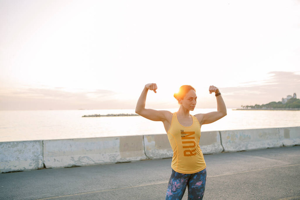 Hardlopen jonge vrouw zonsondergang aan zee, aerobics en yoga doen in het park - Foto, afbeelding