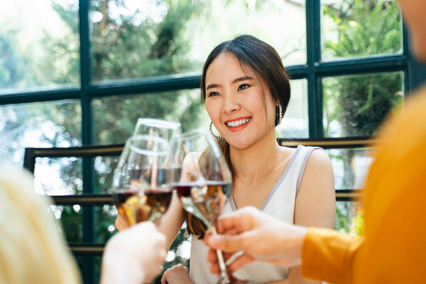 Gyönyörű ázsiai nő bulizik a barátaival az étteremben. Pirítsd meg a borospoharat. Egészségedre. Barátok ünneplik pezsgővel. - Fotó, kép
