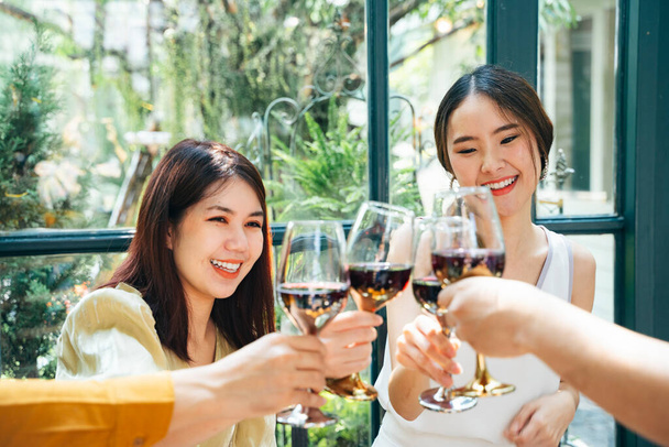 Twee vrolijke aziatische vrouw toasten glazen wijn in restaurant. - Foto, afbeelding