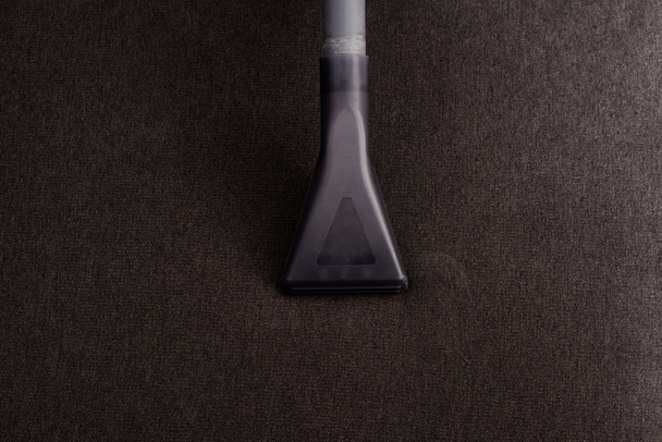 Top view of brush of vacuum cleaner on brown upholstery of sofa  - Zdjęcie, obraz