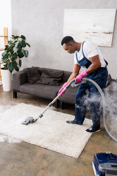 Alfombra de aspiración de limpiador afroamericano con vapor caliente en la sala de estar
 - Foto, Imagen