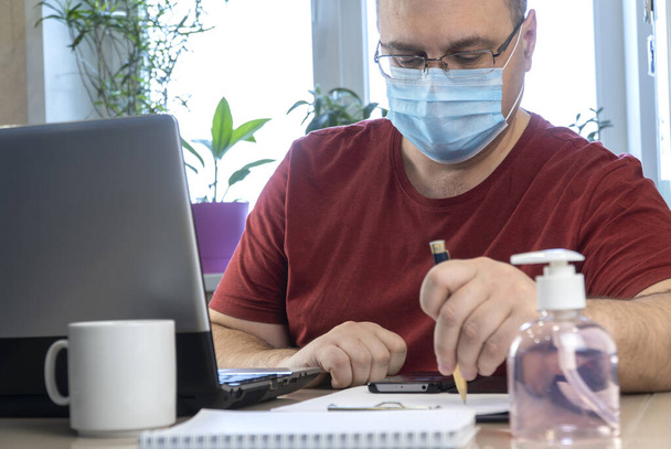 隔離性コロナウイルスパンデミック。家で働いてるビジネスマンは保護マスクをして。抗ウイルス医療用呼吸器包帯の顔。伝染病COVID-19による遠隔作業。内務省 - 写真・画像