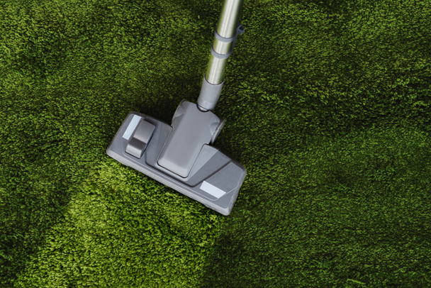 Top view of brush of vacuum cleaner on dirty green carpet  - Foto, afbeelding