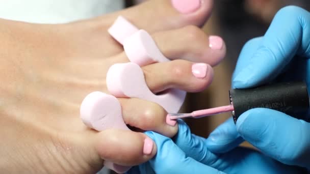 Home salon pedicure. Foot care treatment and nail. The process of professional pedicures. Master in blue gloves apply light pink gel polish.     - Footage, Video