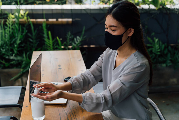 Asian woman in mask disinfecting hands - Valokuva, kuva