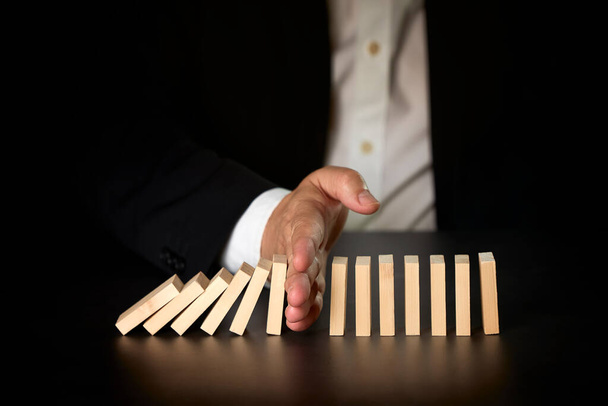 businessman hand stopping falling dominos. Business concept. - Photo, Image