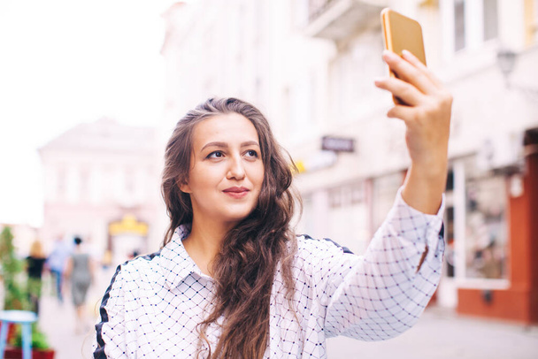 Woman doing selfie while traveling in european city - 写真・画像