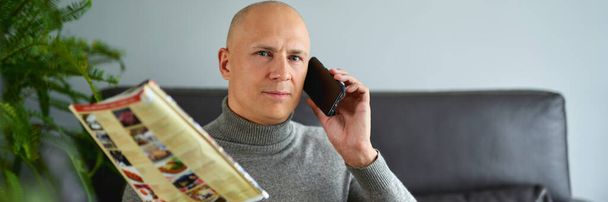Чоловік розмовляє на мобільному телефоні на дивані
 - Фото, зображення
