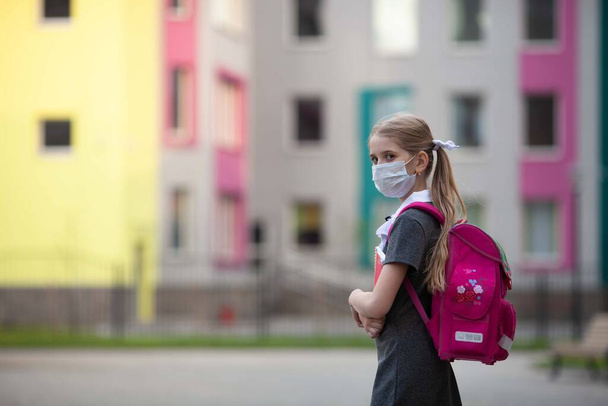 医学部のフェイスマスクをした女子高生が学校の近くにピンクのリュックを背負ったまま通学している。学校に戻る。学校のウイルスからの保護.  - 写真・画像