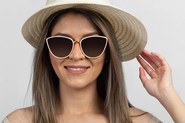 latynoska kobieta uśmiecha się w chłodnych okularach przeciwsłonecznych i kremowym kapeluszu - Zdjęcie, obraz