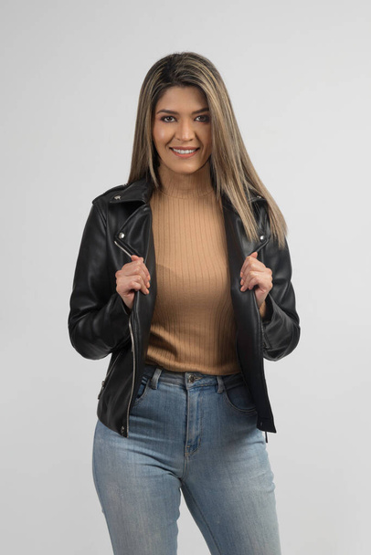 mujer sonriendo con una chaqueta de cuero y jeans - Foto, Bild