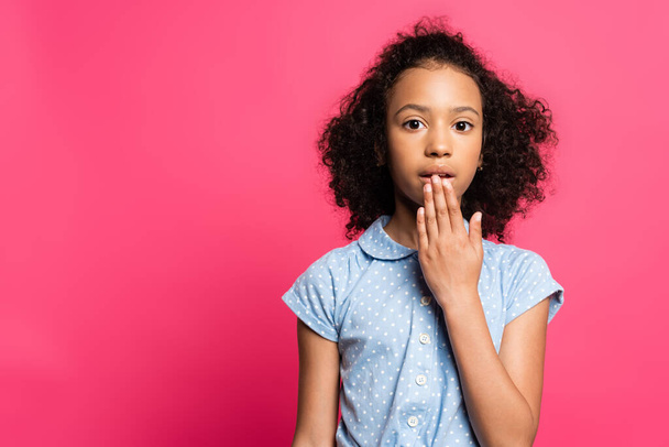 χαριτωμένο σγουρό αφροαμερικανό παιδί που καλύπτει το στόμα απομονώνονται σε ροζ - Φωτογραφία, εικόνα