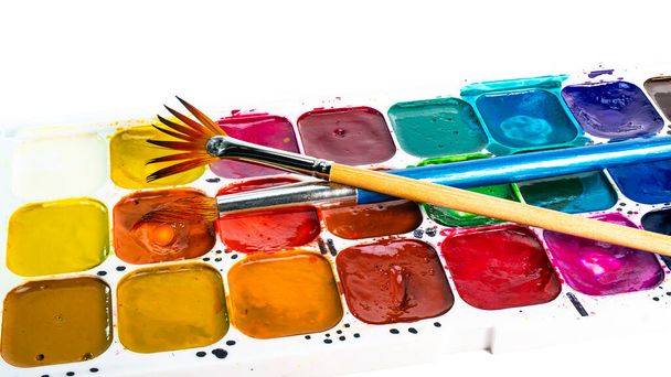 Multi-colored watercolor paints and brushes. Materials for drawing and creativity. Bright water-based paints. School supplies. Hobbies and creativity. - Photo, Image