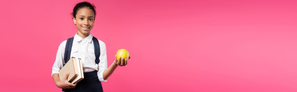 smiling african american schoolgirl with backpack and apple isolated on pink, panoramic shot - Valokuva, kuva