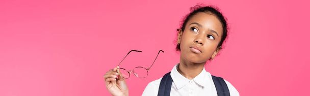 töprengő afro-amerikai iskolás lány szemüveggel elszigetelt rózsaszín, panoráma lövés - Fotó, kép
