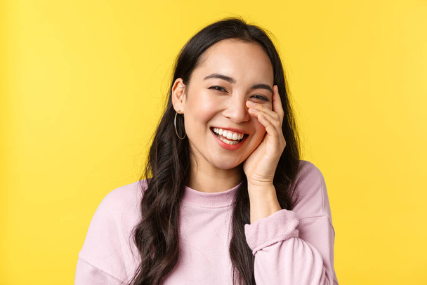 People emotions, lifestyle leisure and beauty concept. Beautiful asian girl touch face and laughing with happy cheerful smile, hear compliment and blushing, stand yellow background - Valokuva, kuva