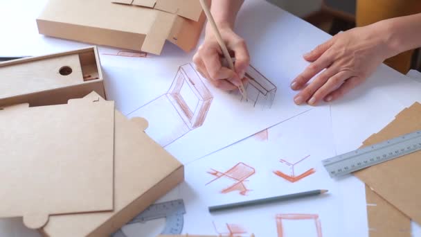  Ontwikkeling van verpakkingsontwerp schets. Designer tekent een mock-up voor het vervaardigen van kartonnen doos.  - Video