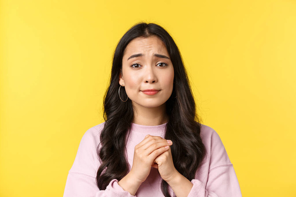 People emotions, lifestyle leisure and beauty concept. Close-up of silly hopeful asian girl pleading or apologizing, holding hands in pray and looking pitiful, yellow background - Фото, изображение