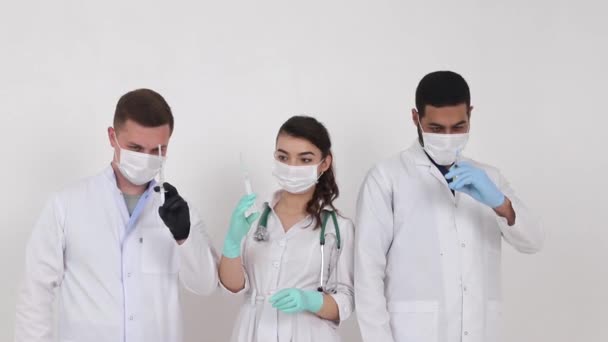 Étudiants en médecine de différents pays sur fond blanc. Heureux étudiants diplômés en médecine avec des seringues dans leurs mains - Séquence, vidéo