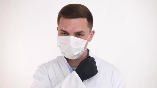 A doctor in a medical mask makes remarks, pointing a finger to the side. Successful young doctor in modern medicine - Video, Çekim