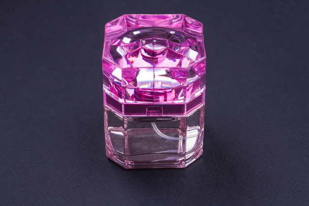Жіночі парфуми в яскраво-рожевій пляшці на темному фоні
. - Фото, зображення