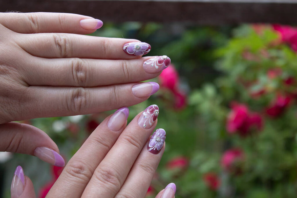  Gotowy piękny manicure dla kobiety. Pomalowane różowe kwiaty. Pomysł zrobienia manicure. Koncepcja piękna. Pasta żelowa, szelak. - Zdjęcie, obraz