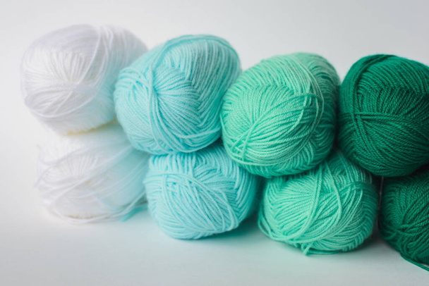 acrylic soft pastel green, azure and white colored wool yarn thread skeins row on white background, side view, horizontal stock photo image background with copy space for text - Zdjęcie, obraz