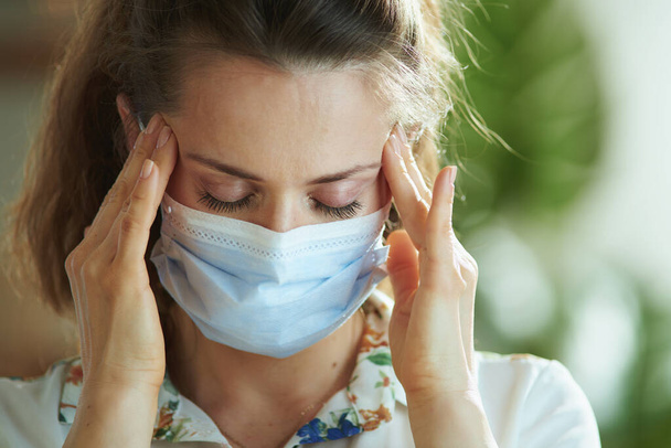 Life during coronavirus pandemic. Portrait of stressed modern woman in white blouse with medical mask. - Photo, Image
